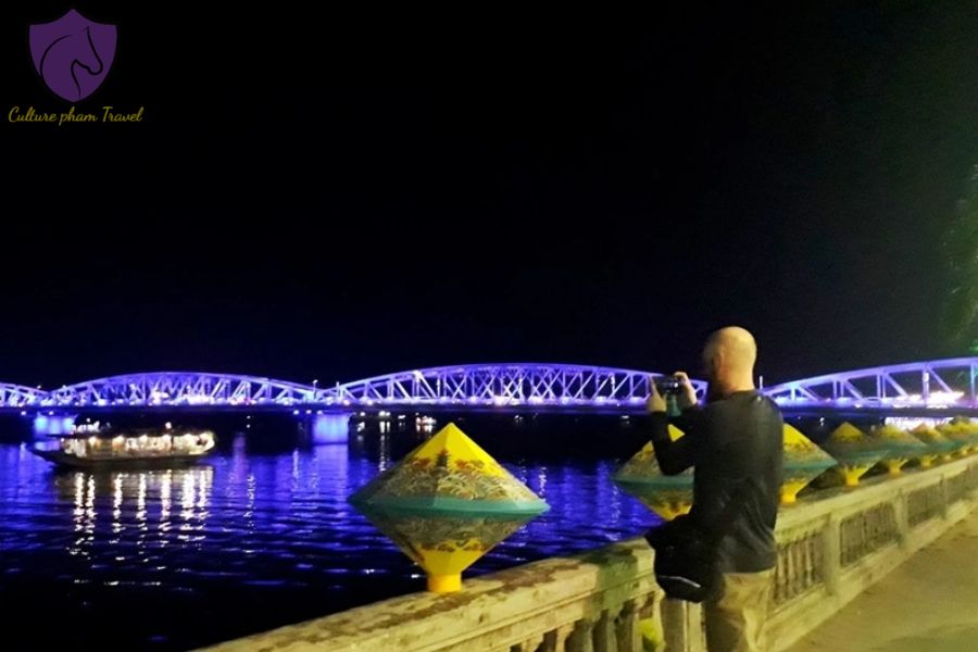 A tourist capturing the colorful bridge at night